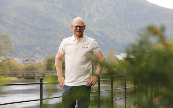 Bildet viser Tasle Torrisen Knapstad foran et rekkverk og en elv.